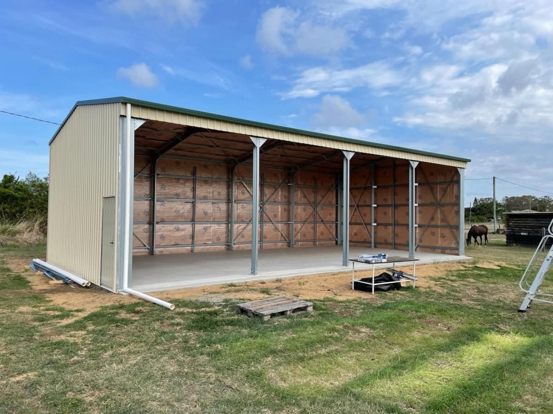 An open-front machinery shed built on a rural block with timber framing inside