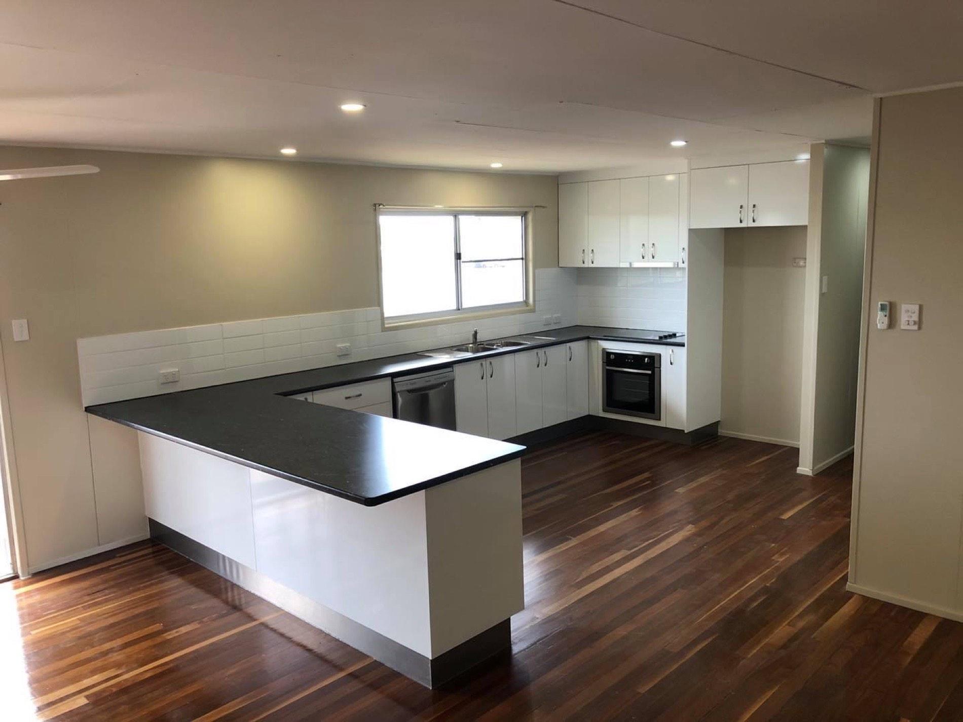 A finished kitchen with an island bench and timber flooring