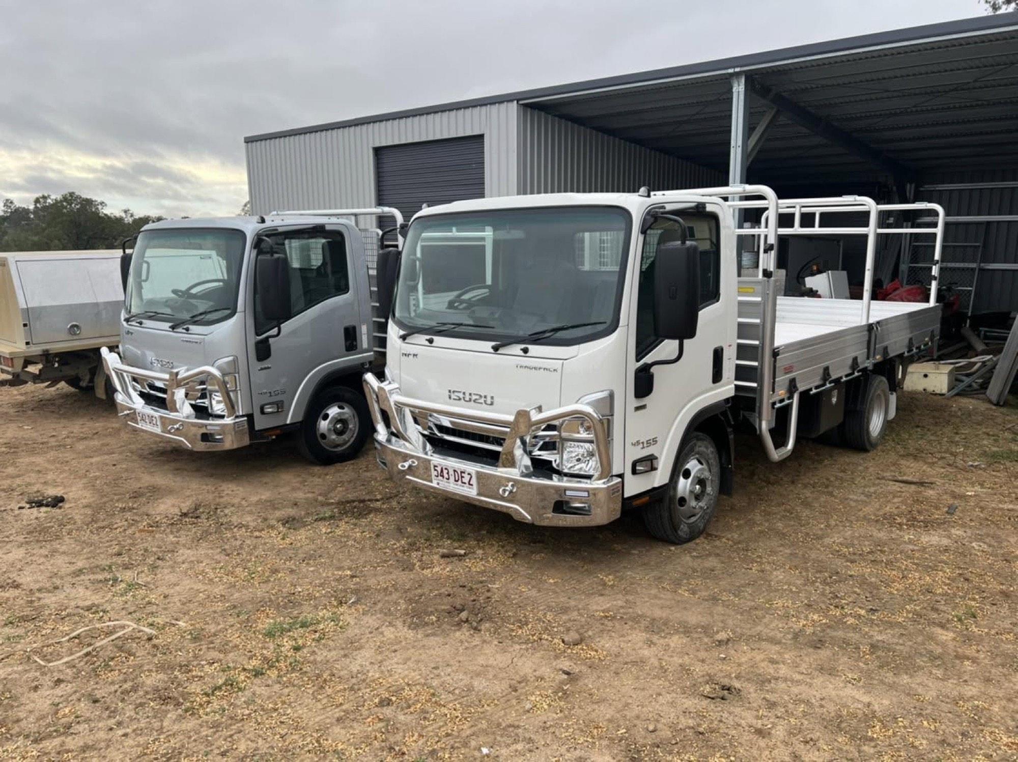 Two MCG Projects trucks parked at the yard beside a shed