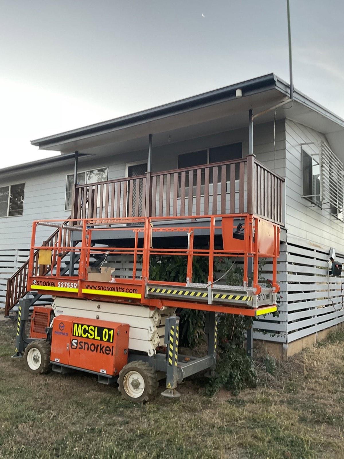 A scissor lift set up against a building being refurbished