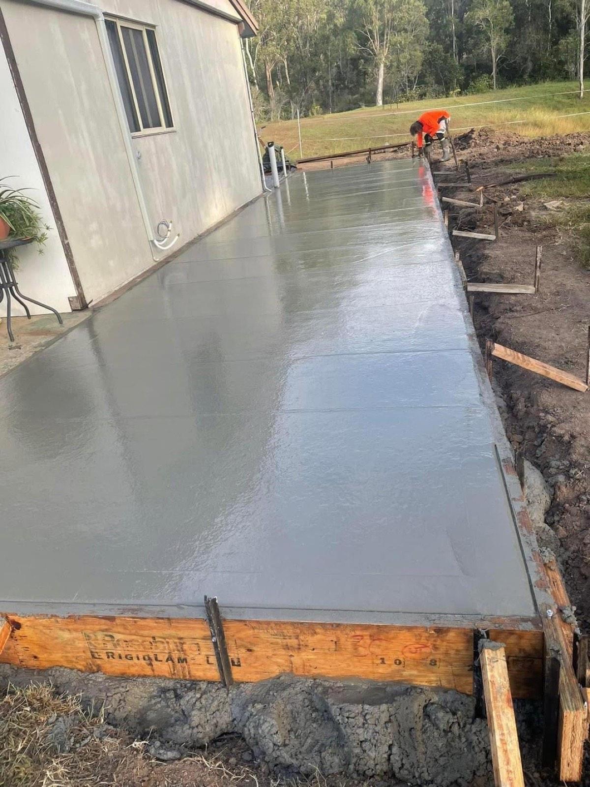 Fresh concrete poured and screeded flat between timber formwork beside a house