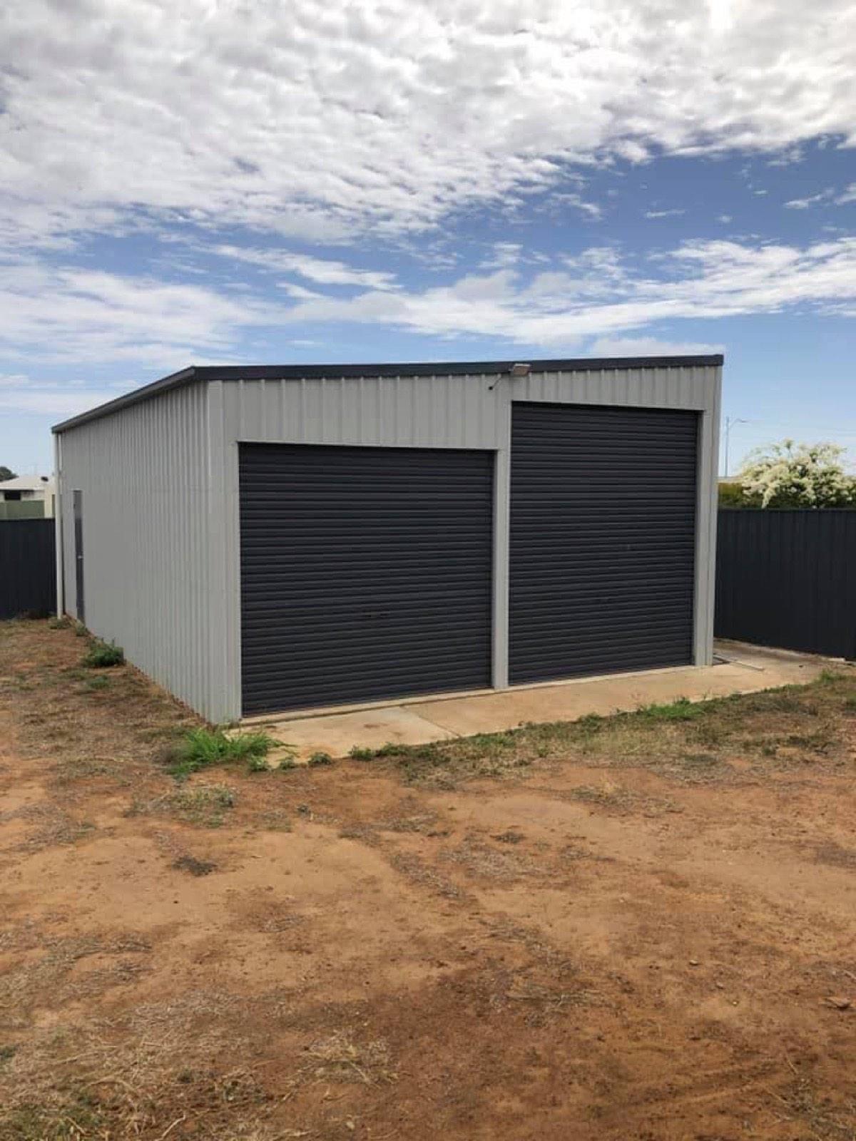A completed Colorbond shed with two roller doors on a cleared rural block
