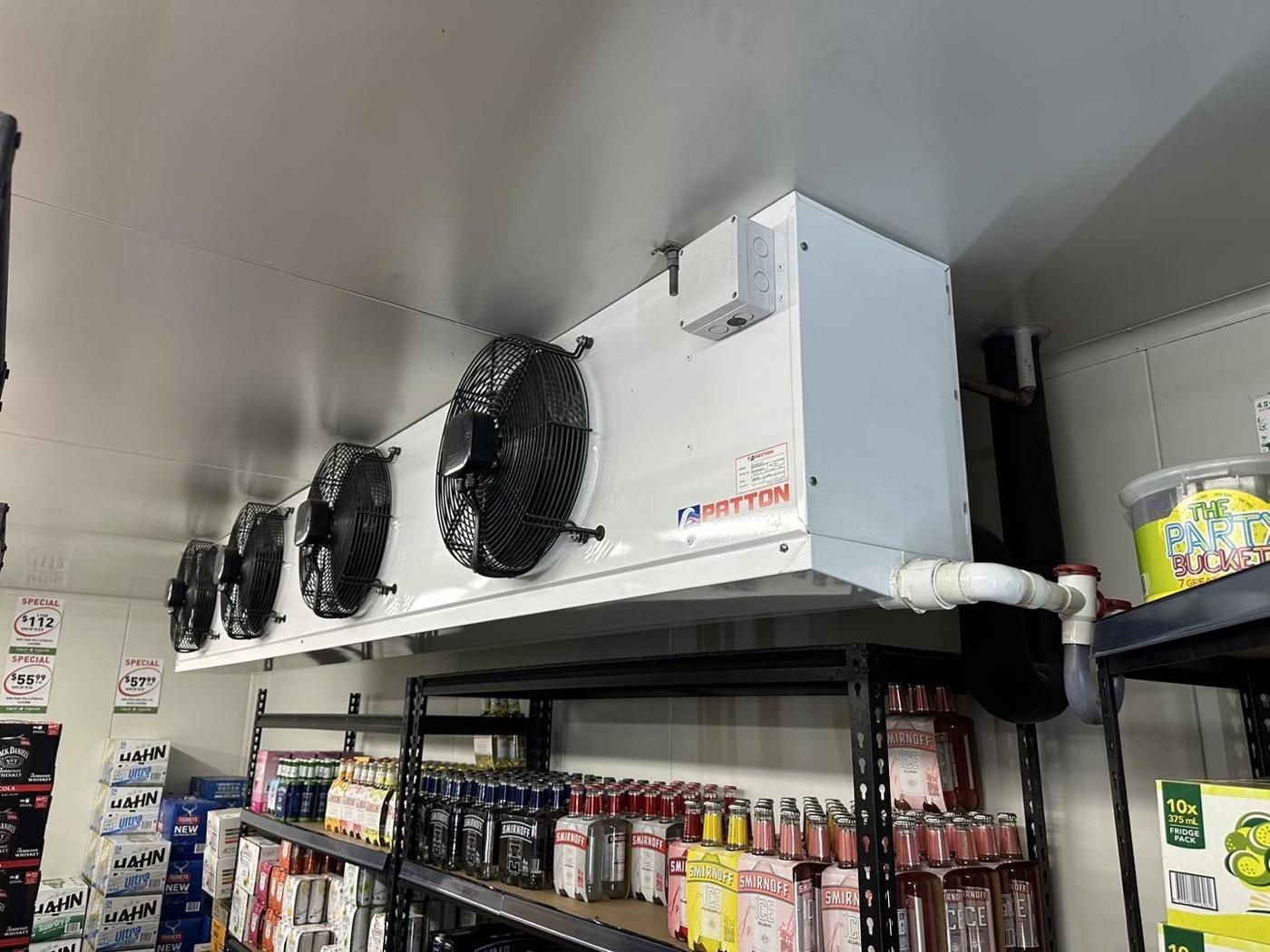 A refrigeration evaporator unit installed above shelving inside a cool room