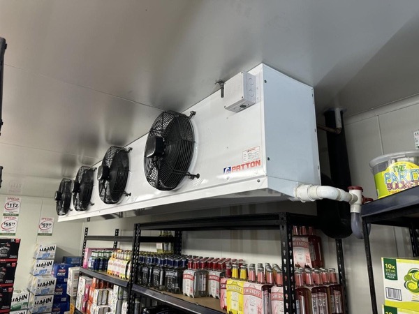 A refrigeration evaporator running above stocked shelving in a cool room