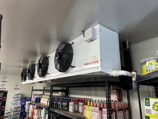 A large evaporator fan unit mounted above stocked shelving