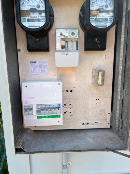 An open meter box with meters, fuses and a new circuit breaker board