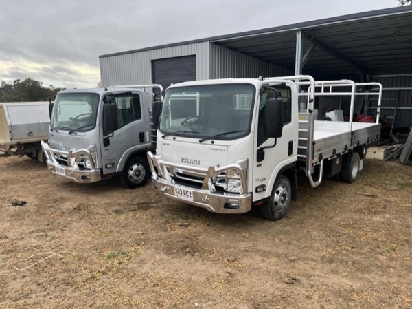 Two work trucks parked at the yard beside a shed