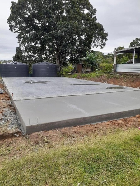 A finished concrete slab poured beside two water tanks