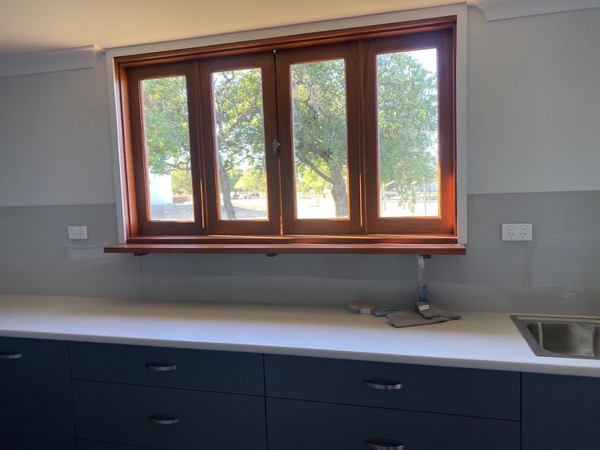 A kitchen bench and splashback below a timber framed window
