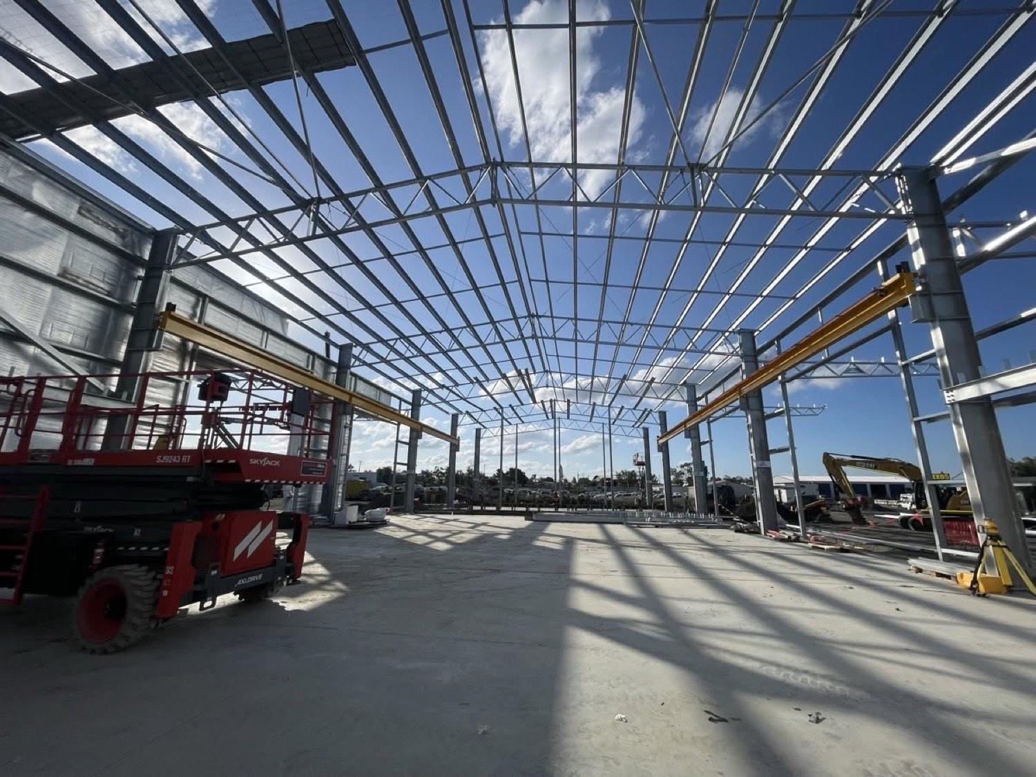 The steel frame of a large commercial building with a telehandler on the slab